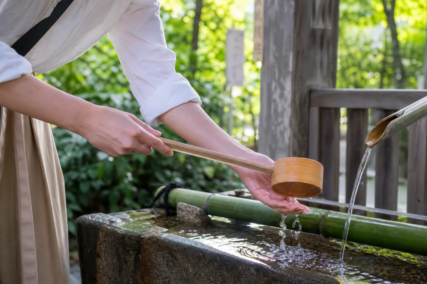 神社の手水舎で柄杓を使って手を清める様子