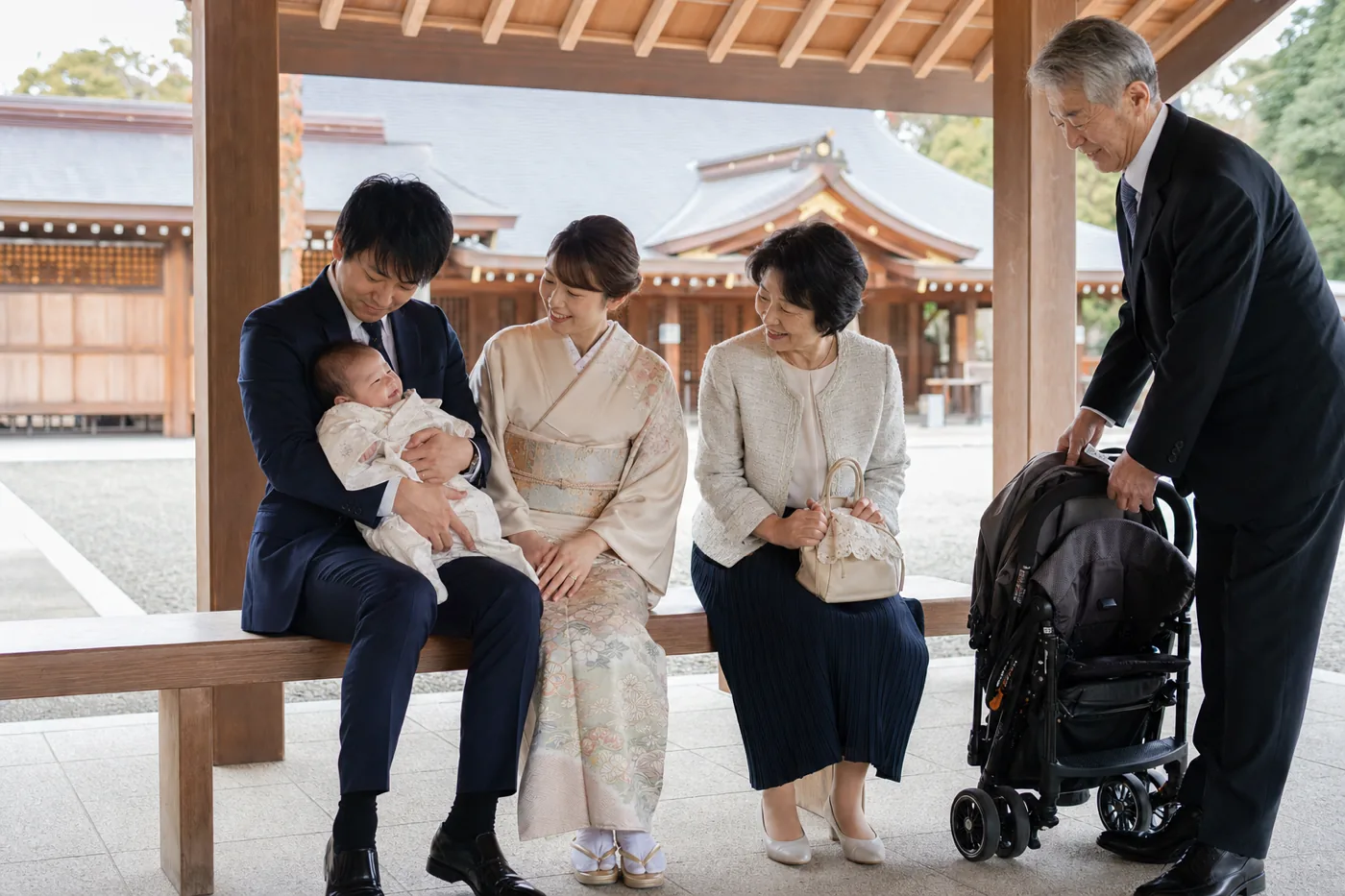 神社の待合所で赤ちゃんを抱く父親と役割分担する家族