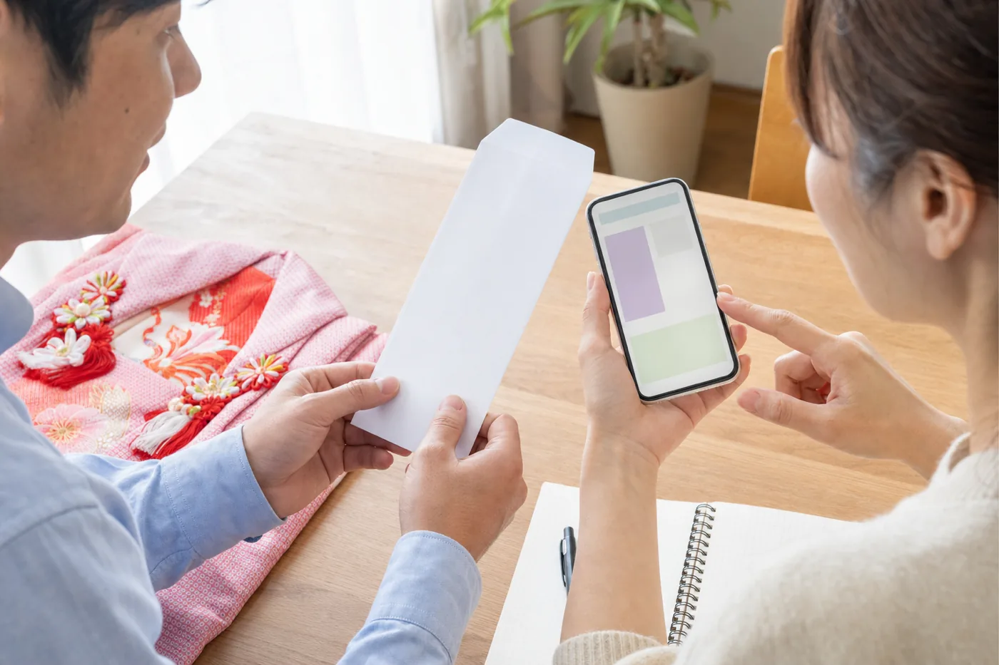 スマートフォンで七五三の初穂料を確認する両親