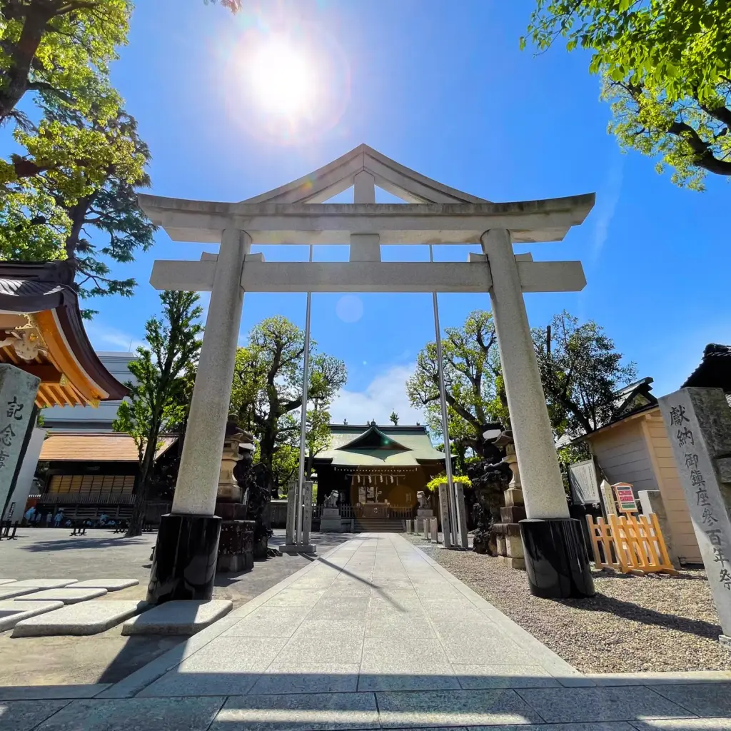 青空の下に立つお三の宮日枝神社の石造りの鳥居と境内